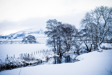 Fototapeta na wymiar Winter snow landscape with trees and hills in background UK