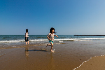 Fototapeta na wymiar 海岸で海遊ぶをしている子供姉妹