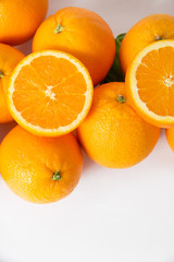 Bunch of whole and cut orange fruits isolated on white background. Closeup, vertical shot, top view. Natural vitamin or organic food concept