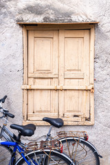 Fototapeta na wymiar Eine Hausmauer mit alten Holzfensterläden und zwei Fahrräder als Hintergrund