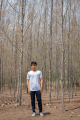 Asian Thai man in white casual stands alone in dry pie forest.