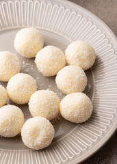 Handmade coconut truffles on a gray plate.