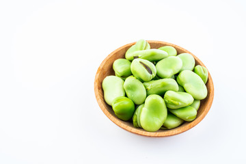 Fresh broad beans in a saucer on white background