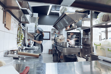 Behind the scenes of brands. The chef cooking in a professional kitchen of a restaurant meal for client or delivery. Open business from the inside. Meals during the quarantine. Hurrying up, motion.