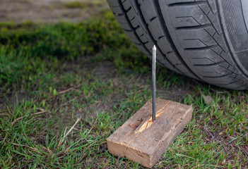 Iron nail in front of car wheel, puncture