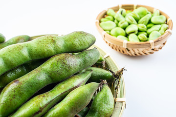 Fresh broad bean pods and broad beans on white background