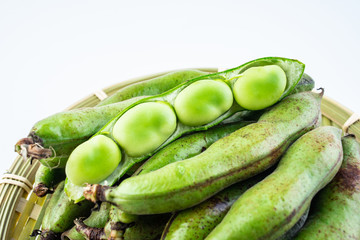 Fresh broad bean pods and broad beans on white background