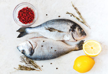 Fresh raw Dorado fish on a white table with cooking ingredients. Top view with a copy of the space, selective focus