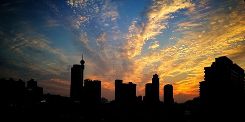 Obraz na płótnie Canvas Silhouette Of City Against Cloudy Sky During Sunset