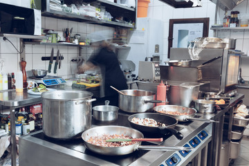 Behind the scenes of brands. The chef cooking in a professional kitchen of a restaurant meal for client or delivery. Open business from the inside. Meals during the quarantine. Hurrying up, motion.