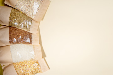 Paper-cellophane bags of cereals, legumes close-up on beige. Copy space. Stock for a rainy day. Stock for quarantine.