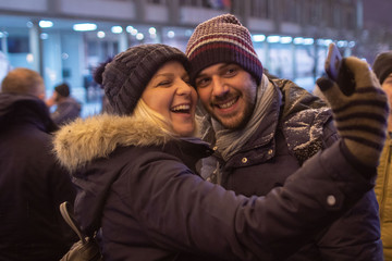 Young couple smiling and taking a selfie during winter festival