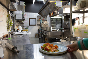 Behind the scenes of brands. The chef cooking in a professional kitchen of a restaurant meal for client or delivery. Open business from the inside. Meals during the quarantine. Hurrying up, motion.