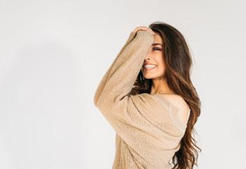 Charming smiling asian girl with long brownw hair in beige sweater looking at camera isolated on the white background