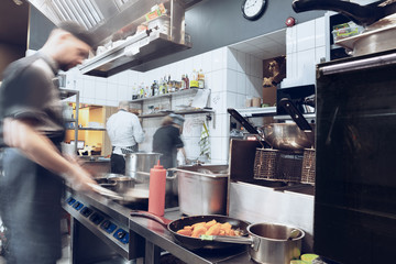 Behind the scenes of brands. The chef cooking in a professional kitchen of a restaurant meal for client or delivery. Open business from the inside. Meals during the quarantine. Hurrying up, motion.