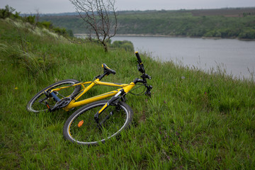 Yellow bicycle on green grass by the river