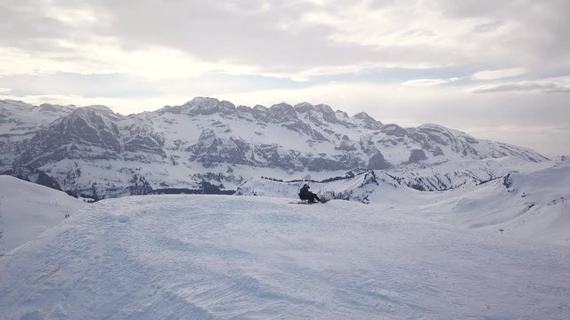 Aerial - Drone circle shot of two skiers sitting on a bench on the edge of a mountain at the skislope Portes Du Soleil in 4K