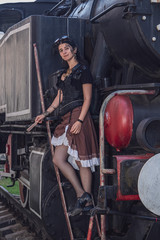 Obraz na płótnie Canvas Beautiful girl in steampunk clothes on the background of the train