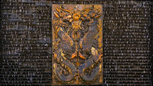 Traditional Thai Fountain at the temple in Thailand. Image of two dragons in the center of a vertical fountain. Water flows through the sloping partitions