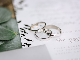 wedding silver engagement rings with fingerprint engraving inside. Lying on paper with calligraphy....