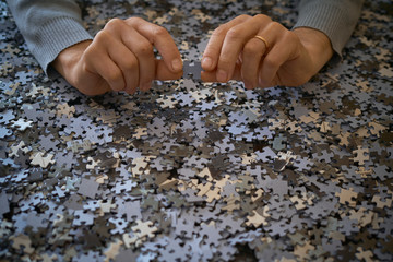 Hands hold a puzzle piece on a background of pieces