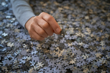 Hand shows a puzzle piece on a background of pieces