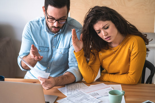 Worried unhappy couple arguing about debt or high domestic bills with laptop and documents stock photo