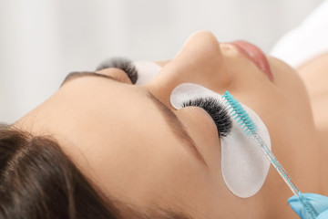 Eyelashes extensions. Fake eyelashes. Eyelash extension procedure.Close up portrait of woman eye with long eyelashes. Professional stylist lengthening female lashes. Master and client in beauty salon.