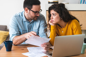 Photo of young loving couple discussing about domestic bills at home.  Sad woman look at man stock...