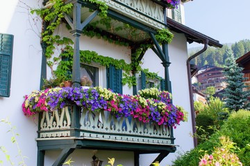 Traditional tirol house balcony decorated with varieties of petunia and surfinia flowers, Dolomites...
