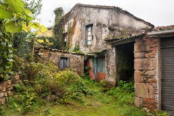 Fototapeta premium An old destroyed abandoned house in Spain, Europe. Broken windows, damaged walls and overgrown garden.