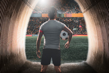 Football player with ball in hand at the entrance to the stadium.