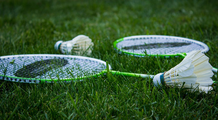 Two badminton rackets and shuttlecocks lying on green grass
