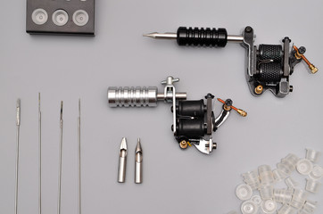 Tattoo machines, needles and all these tattoo stuff isolated on grey background. Tattoo guns. Pattern with tattoo machine, wallpaper for your business design