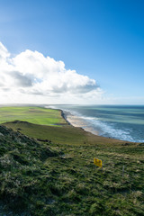 Fototapeta na wymiar Beach, sea and green fields at Escalles on the Opal coast in northern France close to Cap Blanc Nez on a sunny day with blue sky and clouds