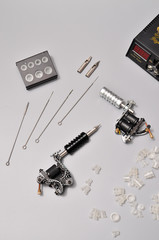 Fototapeta premium Tattoo machines, needles and all these tattoo stuff isolated on grey background. Tattoo guns. Pattern with tattoo machine, wallpaper for your business design