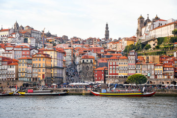 Fototapeta na wymiar Porto, The Ribeira District, Portugal old town ribeira view with colorful houses, traditional facades, old multi-colored houses with red roof tiles, Douro river and boats.