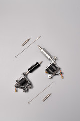Tattoo machines, needles and all these tattoo stuff isolated on grey background. Tattoo guns. Pattern with tattoo machine, wallpaper for your business design