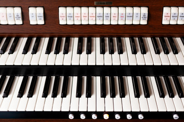 New modern pipe organ keyboards front view. Simple double electronic instrument keyboard seen from above, frontal shot, closeup. Church sacral music classical concert background