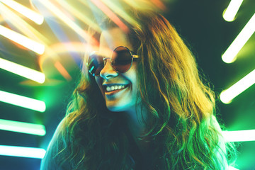 Cheerful cute smiling girl in round glasses at neon background.
