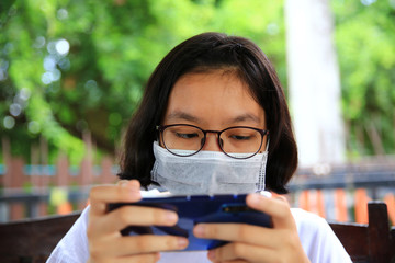 Portrait young woman new normal lifestyle , wearing face mask operate mobile during lockdown effect from Coronavirus (Covid-19)