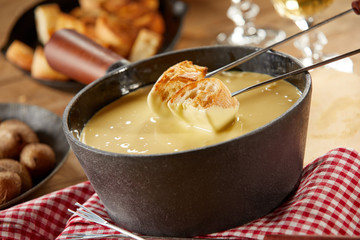 Dipping toasted baguette into a hot cheese fondue