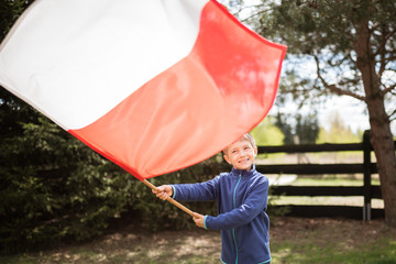 Fototapeta Smiling little boy playing outdoor with polish national red-white flag obraz