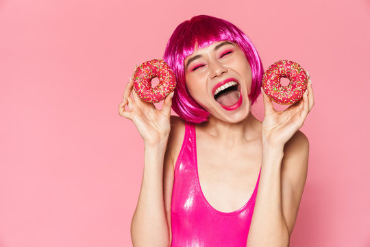 Image of young party girl wearing wig smiling and holding donuts