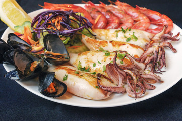 Plate with grilled seafood. Mussels, cuttlefish, shrimp, lemon