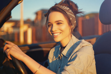 Young beautiful girl sitting in cabrio car on sunset wait for friends and think about perfect weekend so cute smiling to you - obrazy, fototapety, plakaty