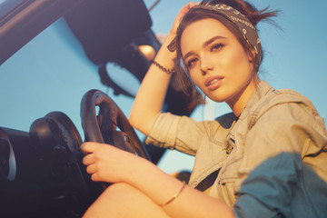 Young beautiful girl sitting in cabrio car on sunset wait for friends and think about perfect...