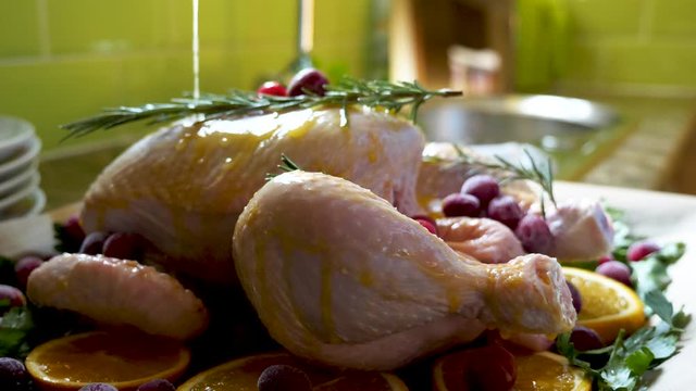 female hands spraying sauce onto raw chicken in baking tray ready for oven