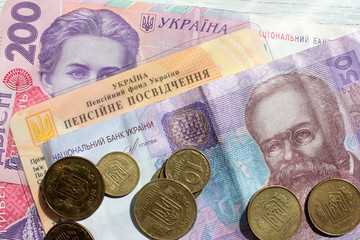 Ukrainian pension certificate and money (paper banknotes of 200 and 50 hryvnias and coins). Close-up, top view