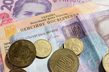 Ukrainian pension certificate and money (paper banknotes of 200 and 50 hryvnias and coins). Close-up, top view
